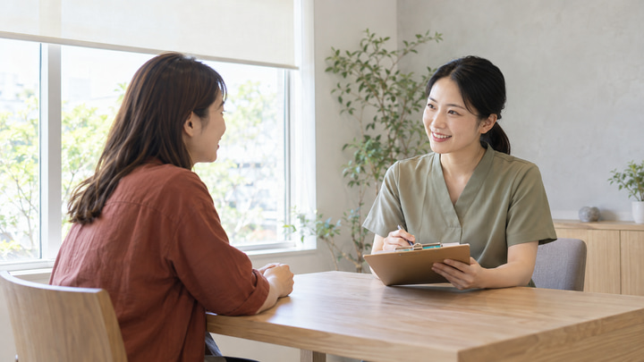 新規背景の一般的なサロンで架空の日本人女性セラピストに相談する女性