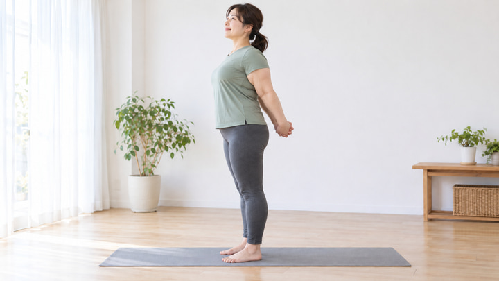 ふくよかな体格の日本人女性が自宅で胸を開くストレッチをする様子
